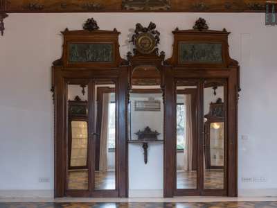 ...l�originale boiserie in noce che riveste le pareti tra porte a specchio...